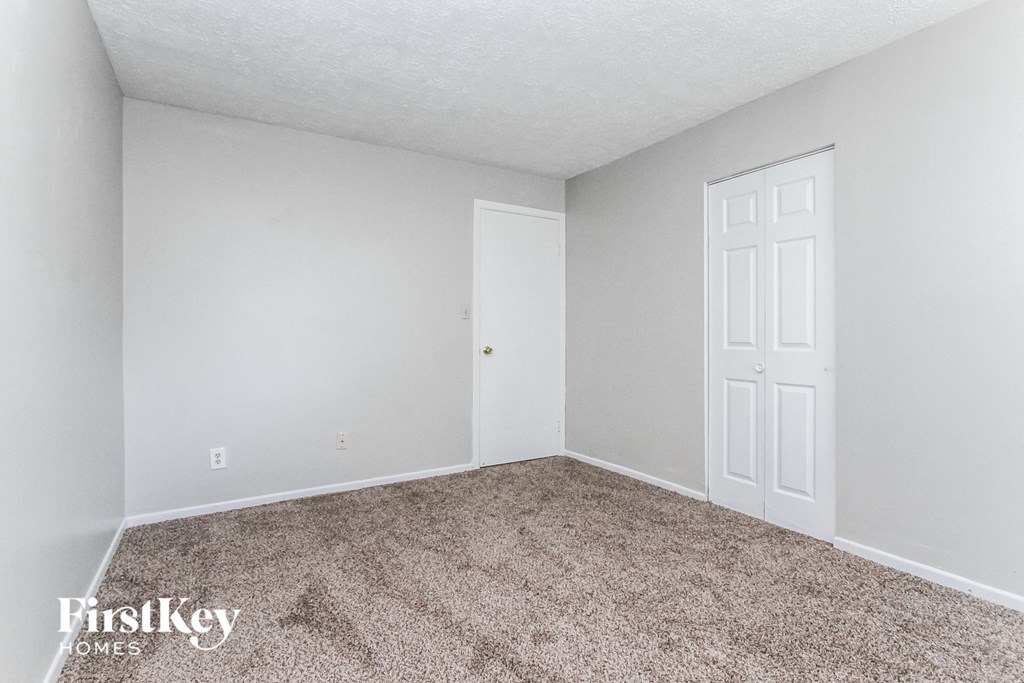 a bedroom with a carpeted floor and a white door