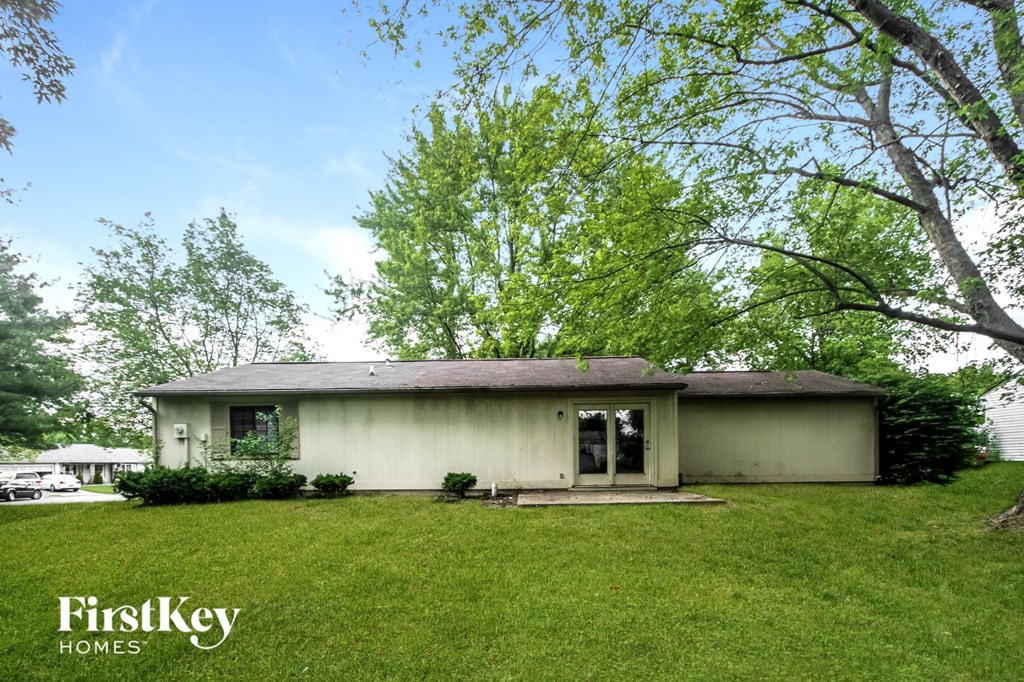 a white house with a grassy yard and trees