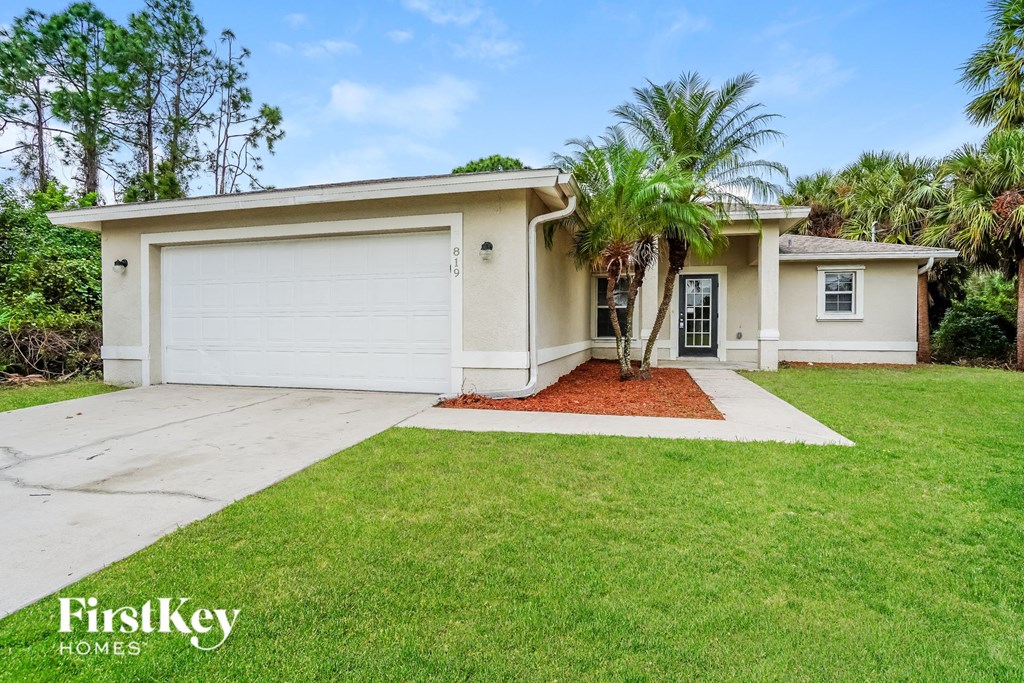 A house with a garage and a palm tree in front.
