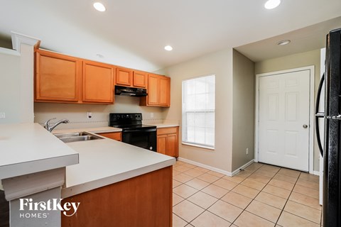a kitchen with wooden cabinets and white counter tops and a black refrigerator