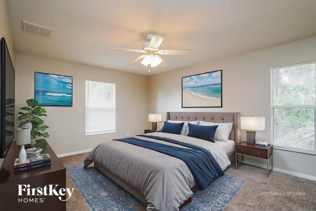A bedroom with a bed, a ceiling fan, and two pictures on the wall.