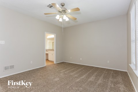 a spacious living room with carpet and a ceiling fan