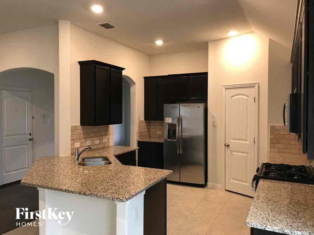 a kitchen with granite counter tops and a stainless steel refrigerator