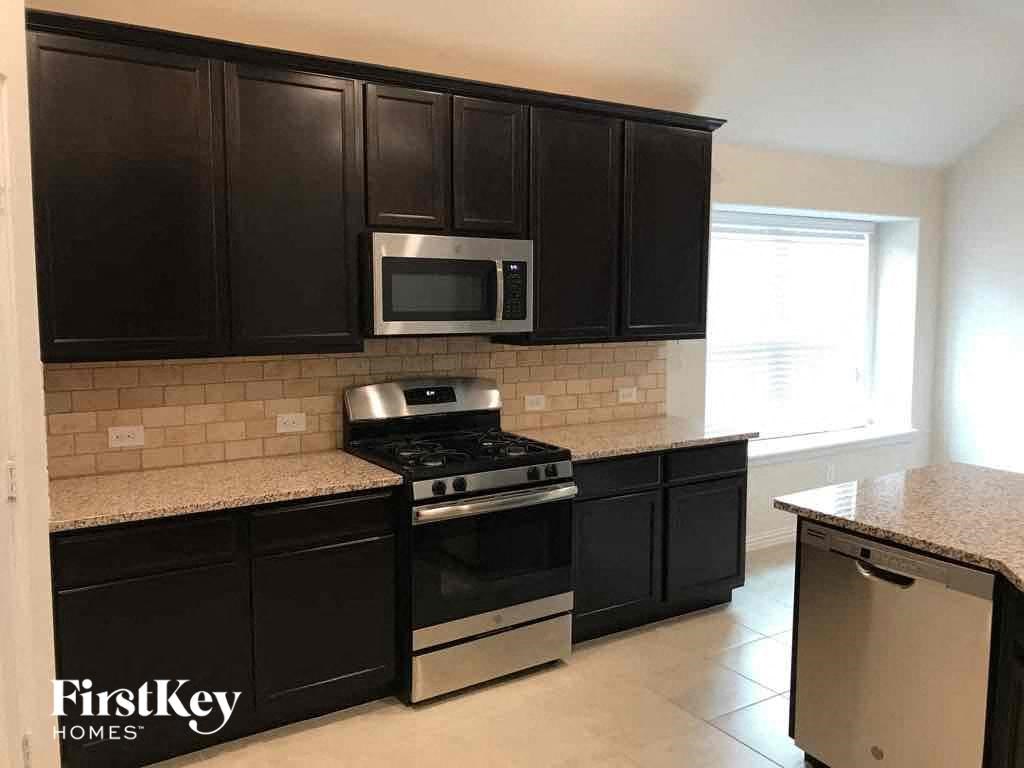 an empty kitchen with black cabinets and stainless steel appliances