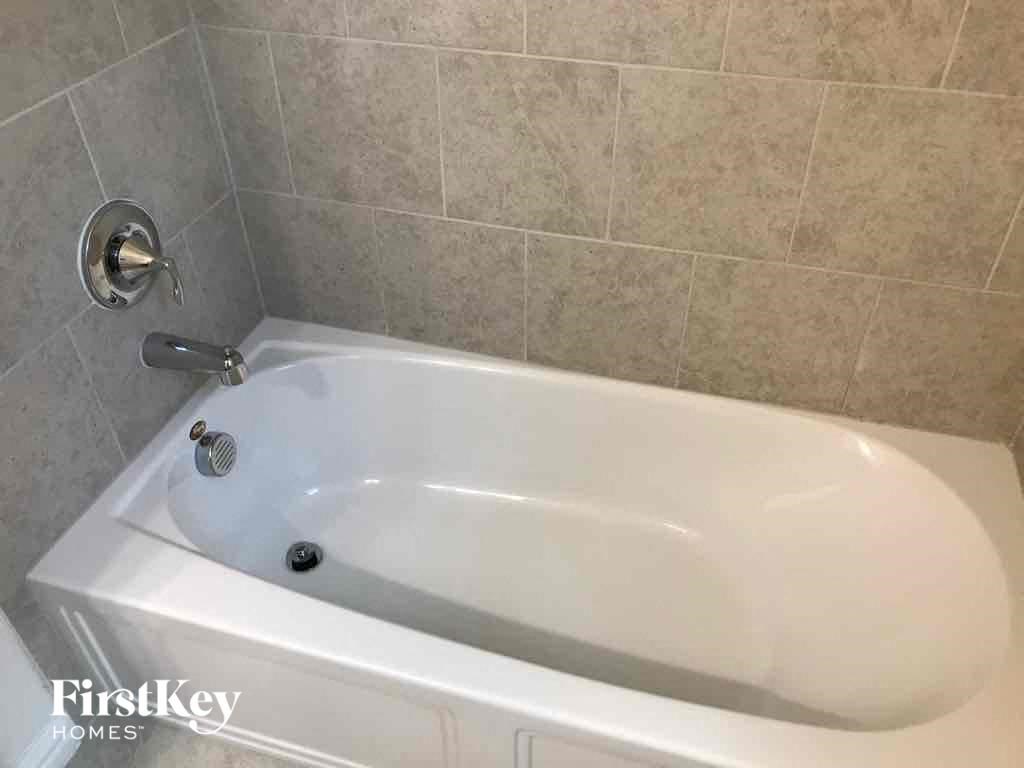 a white bath tub in a bathroom with gray tiles