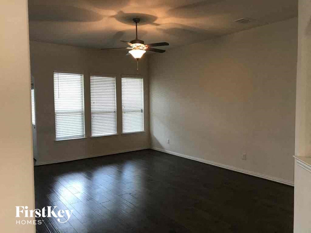 an empty living room with a ceiling fan and window