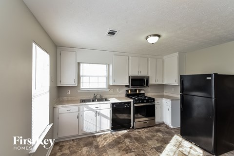 a kitchen with white cabinets and black appliances
