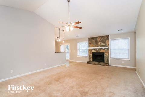A spacious living room with a fireplace and a ceiling fan.