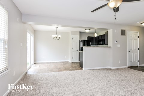 A spacious living room with a ceiling fan and a chandelier.