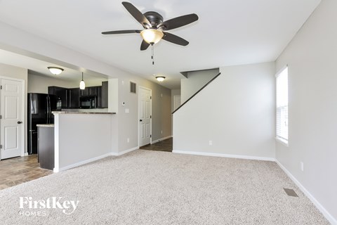 A spacious room with a ceiling fan and a staircase.