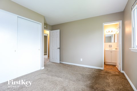 a bedroom with a carpeted floor and a door to a bathroom