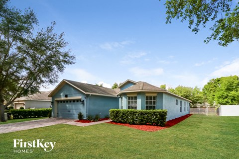 a small blue house with a lawn and a fence