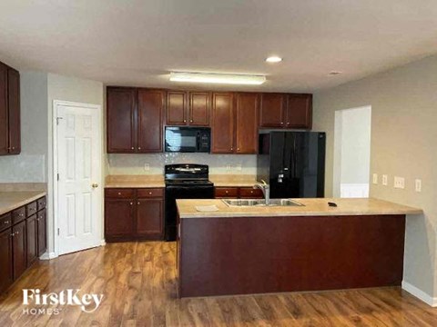 A kitchen with wooden cabinets and a black refrigerator.