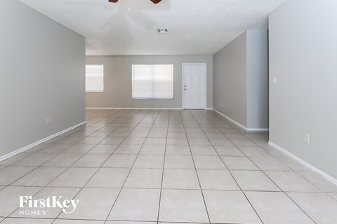 A spacious room with tile flooring and a door on the right.
