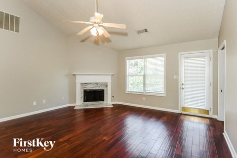A spacious room with a fireplace and wood flooring.