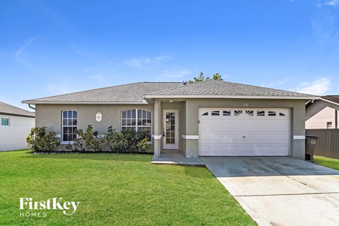 a beige house with a garage door and a lawn