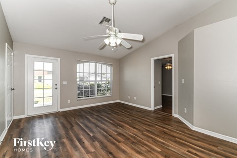 an empty living room with wood floors and a ceiling fan