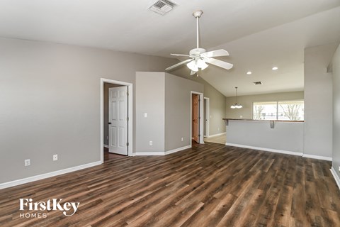 the living room and dining room with wood flooring and a ceiling fan