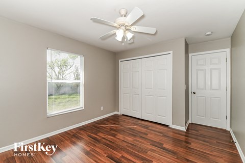 the master bedroom has a hard wood floor and a ceiling fan