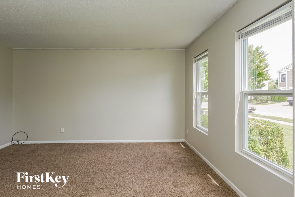 A room with a carpet floor and a window letting in light.