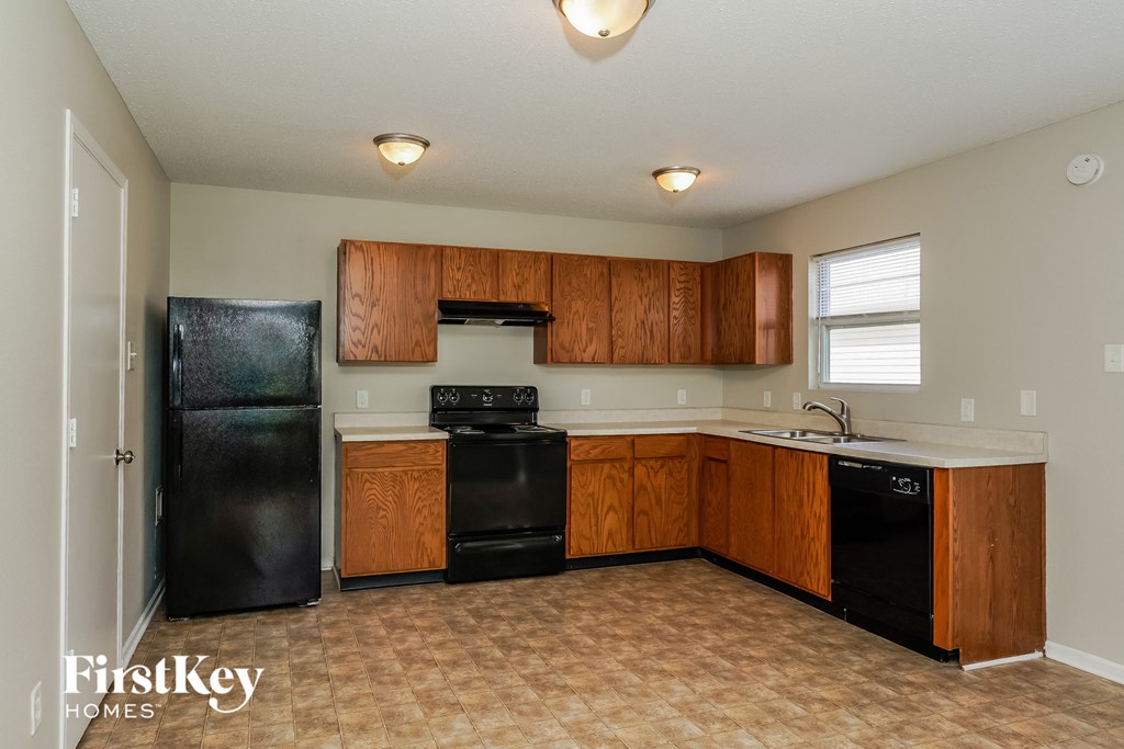 A kitchen with black appliances and wooden cabinets.