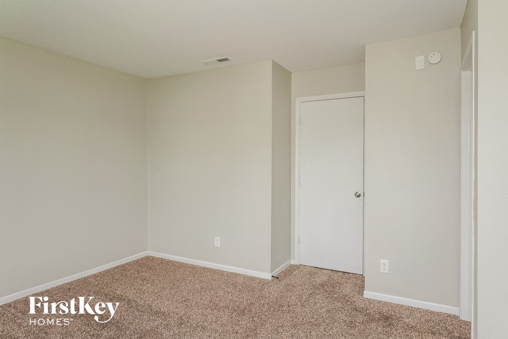 A room with a carpeted floor and a white door.