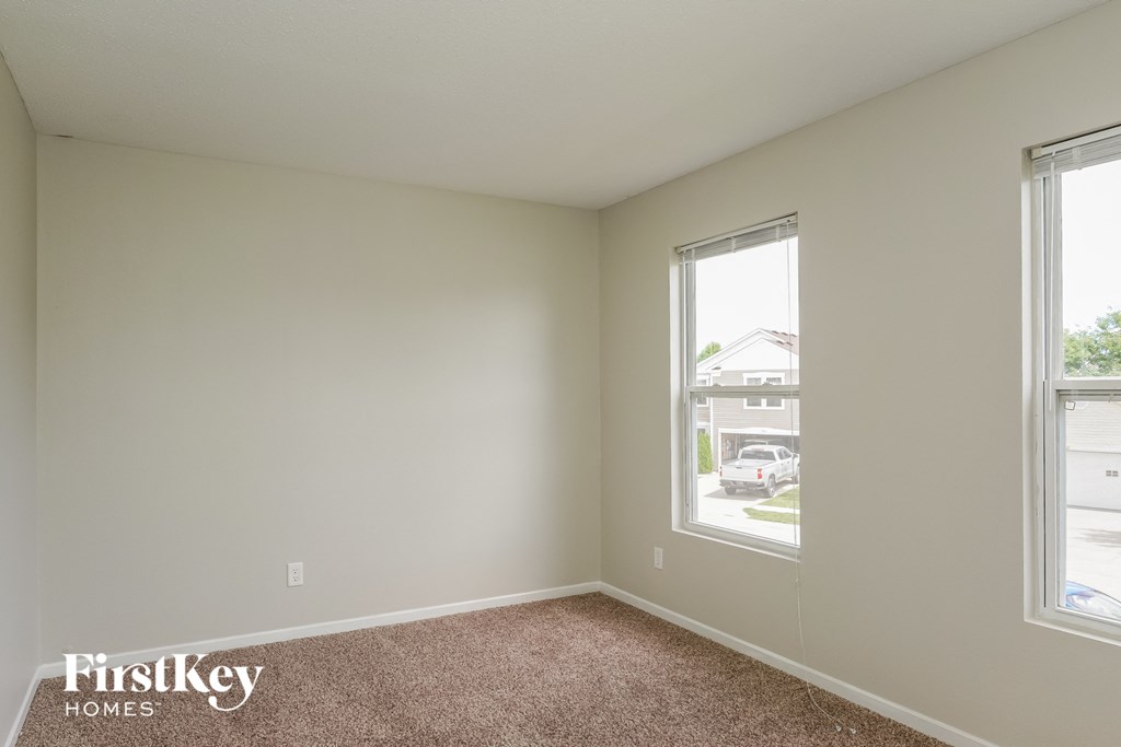 A room with a carpet floor and two windows.