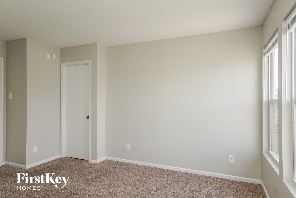 A room with a carpet floor and a window on the right side.