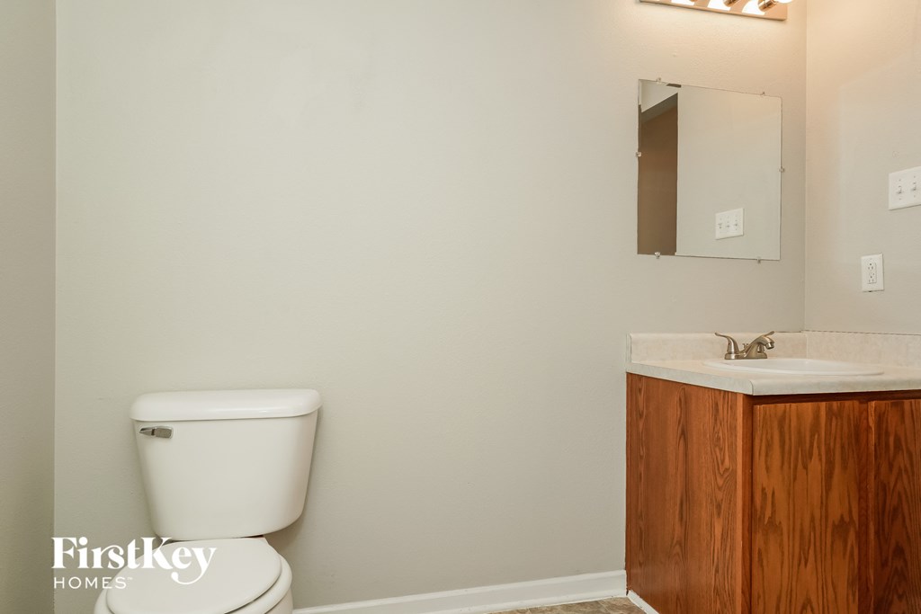 A white toilet sits next to a wooden sink in a bathroom.