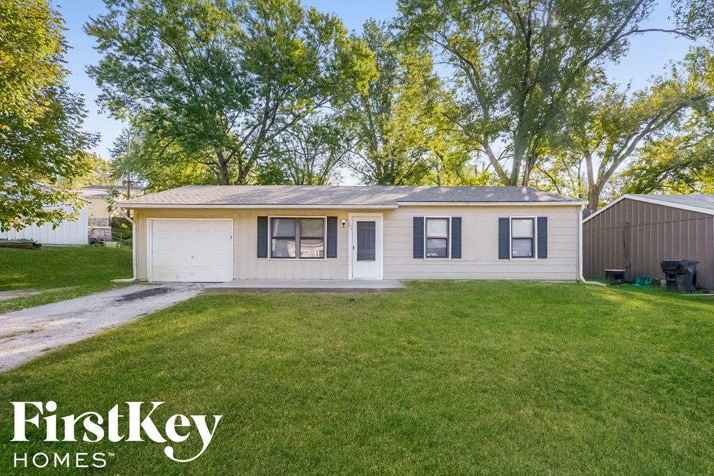 a small white house with a lawn and a driveway
