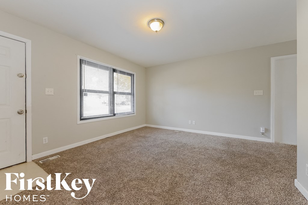 the spacious living room with carpeting and a window