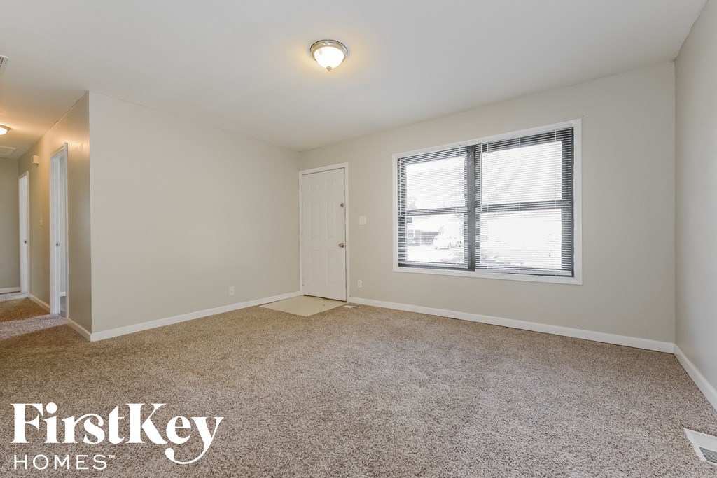 a spacious living room with carpet and a window