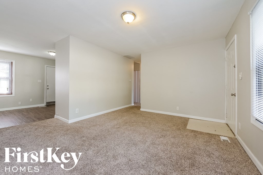 a spacious living room with carpet and white walls