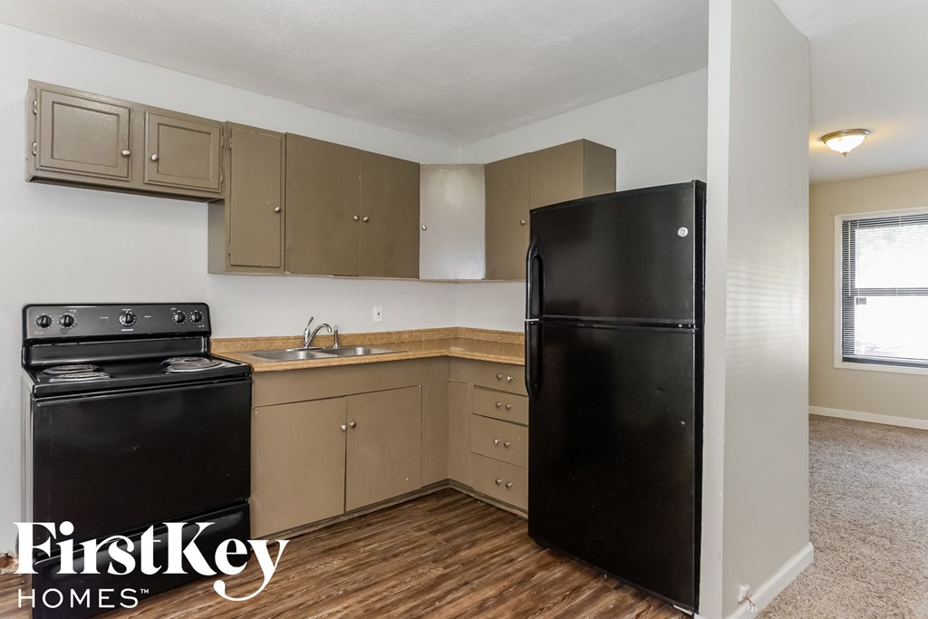 a kitchen with a black refrigerator and a stove and a sink