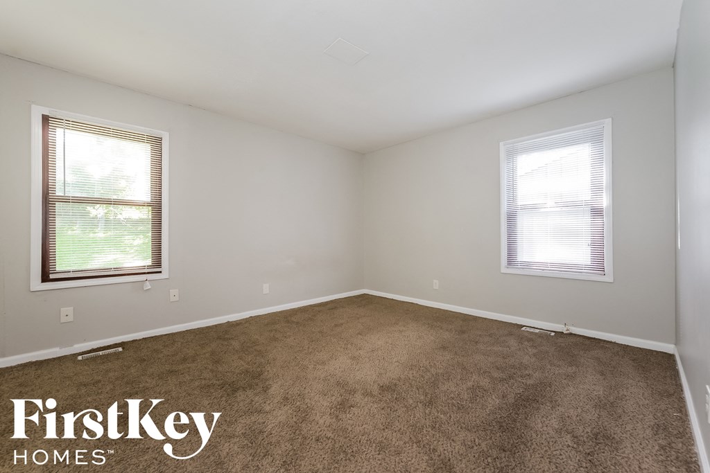 a room with a carpeted floor and two windows