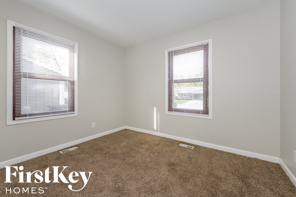 a bedroom with a carpeted floor and two windows