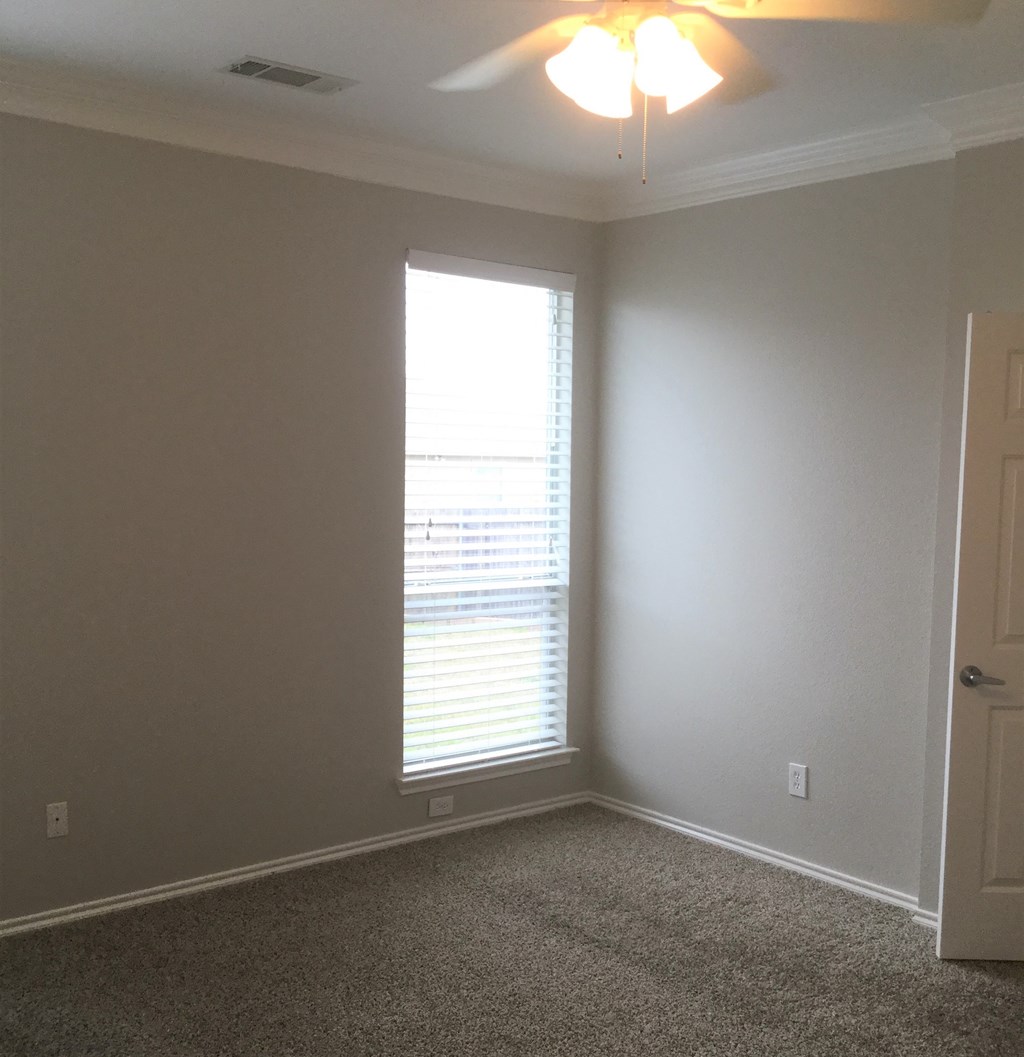 an empty room with a window and a ceiling fan