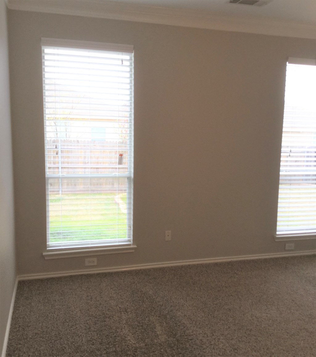 an empty room with two windows with blinds