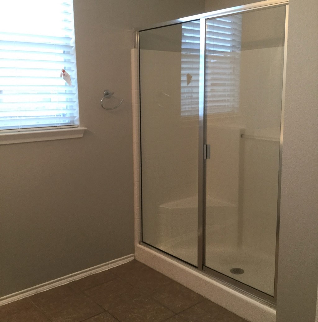 a small shower in a bathroom with a window