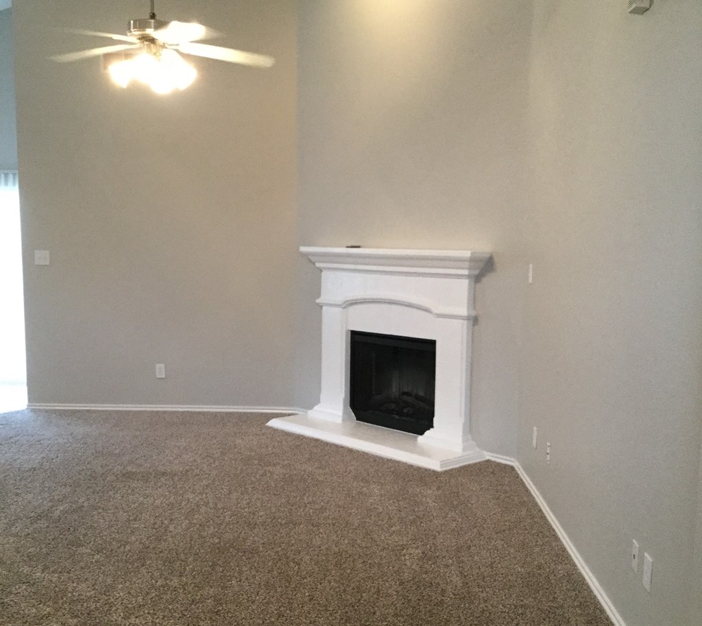 a living room with a fireplace and a ceiling fan