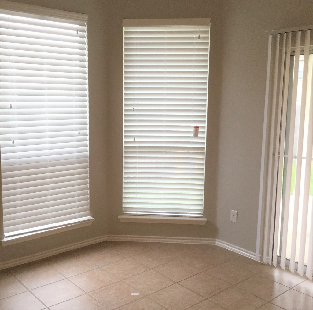 a dining room with two windows with white blinds