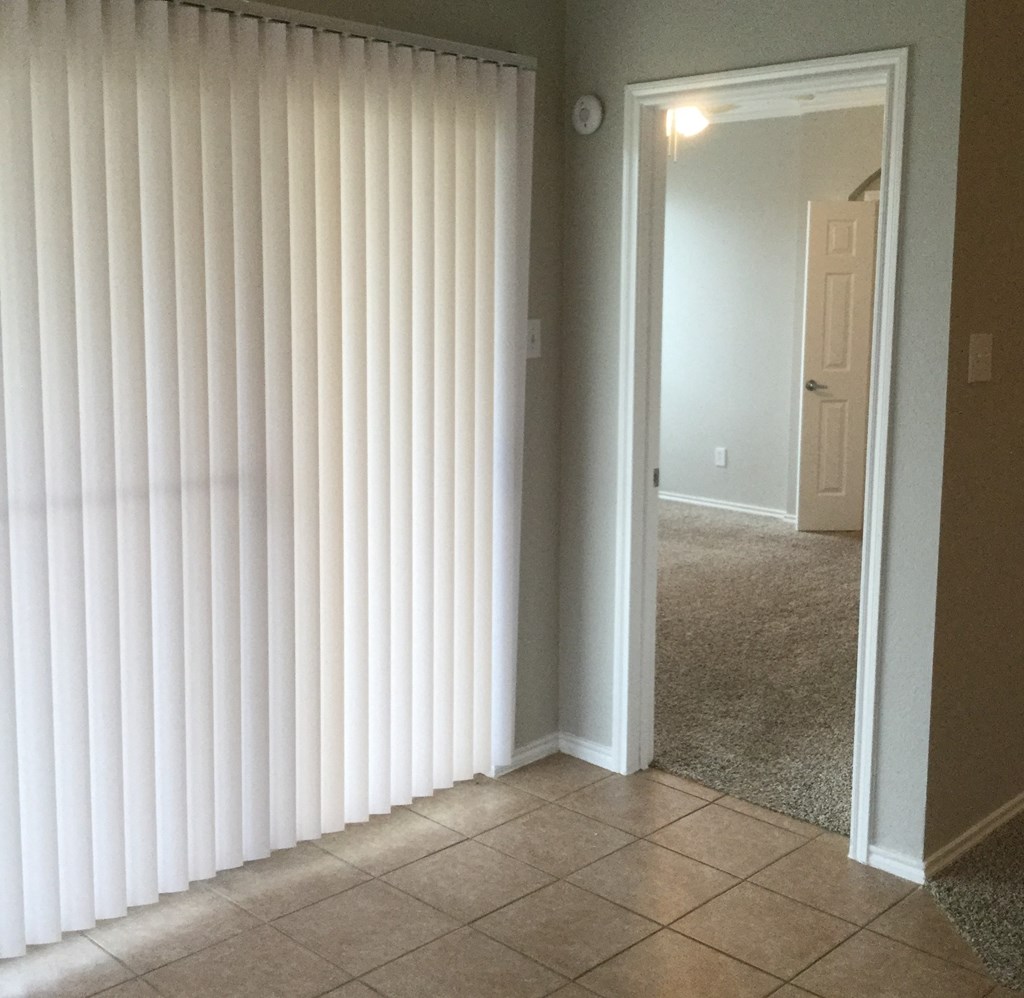 a living room with white blinds on the wall and a doorway