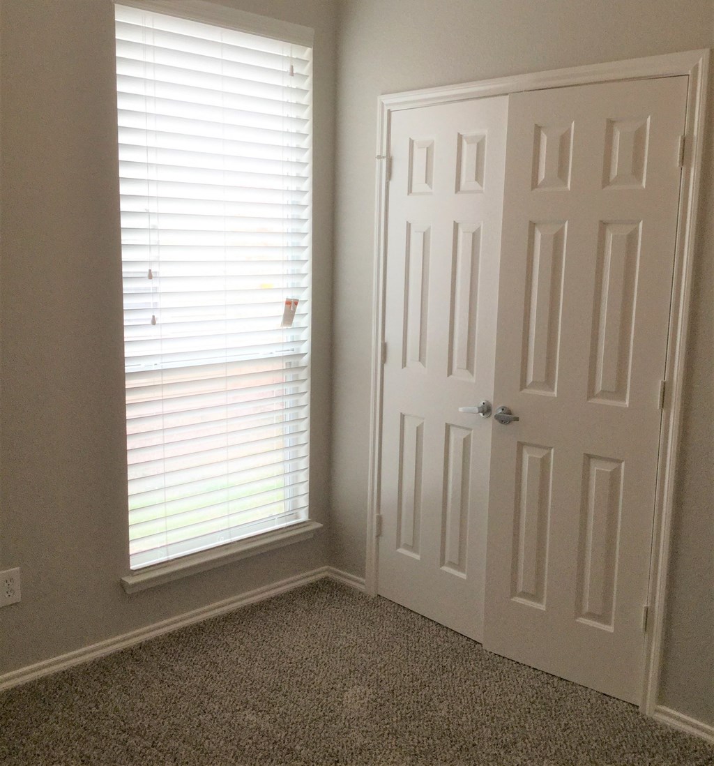 a room with a white door and a window with blinds