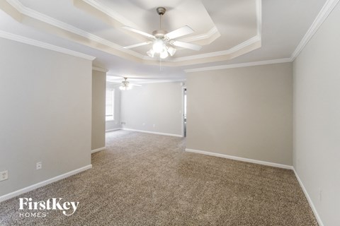a spacious living room with a ceiling fan and carpet
