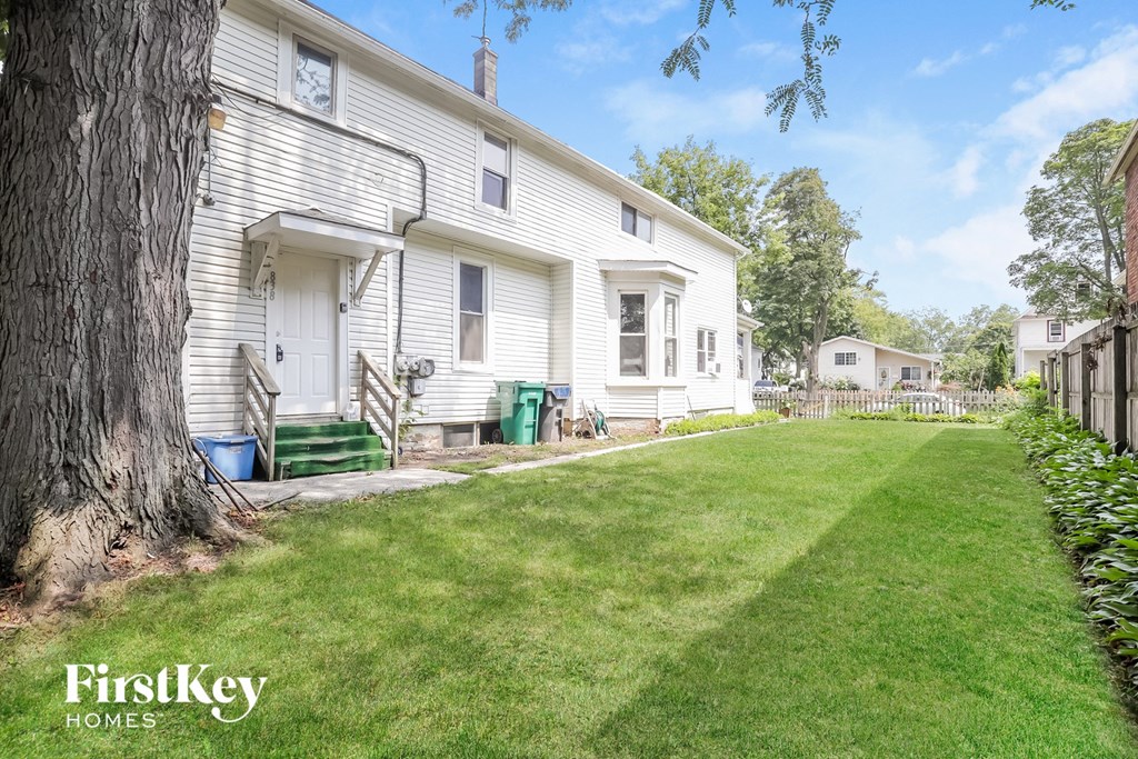 a white house with a lawn and a tree in front of it