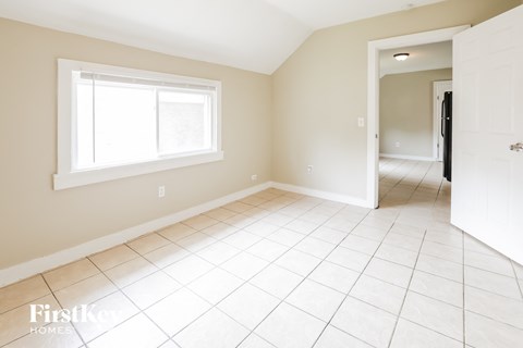 an empty living room with a window and a tiled floor