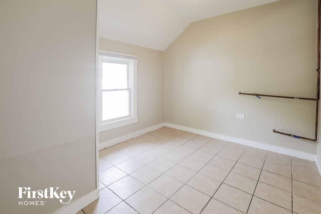 an empty room with white walls and tiled floors and a window