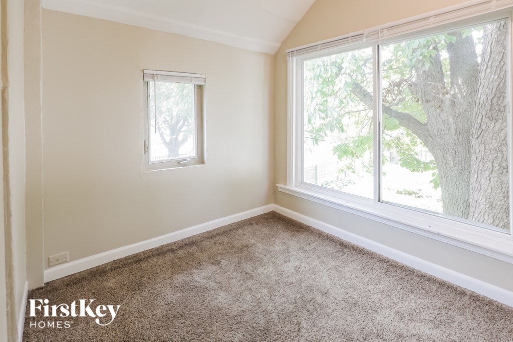 an empty room with a large window and carpet