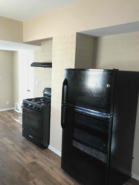 A black refrigerator and oven in a kitchen.