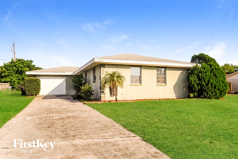 a yellow house with a lawn and a driveway